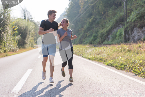 Image of young couple jogging along a country road