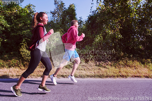 Image of young couple jogging along a country road