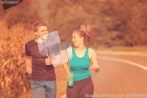 Image of young couple jogging along a country road