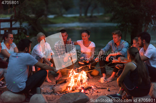 Image of young friends relaxing around campfire
