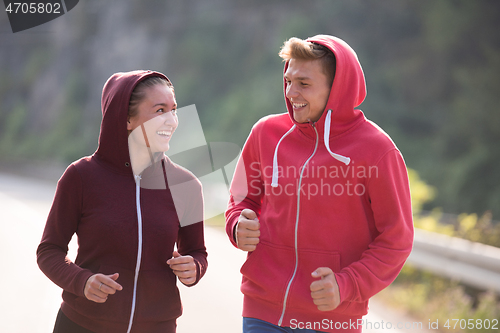 Image of young couple jogging along a country road