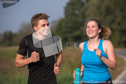 Image of young couple jogging along a country road