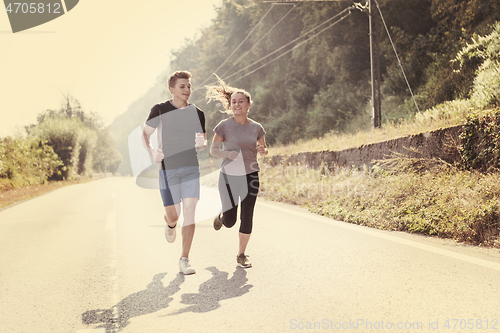 Image of young couple jogging along a country road