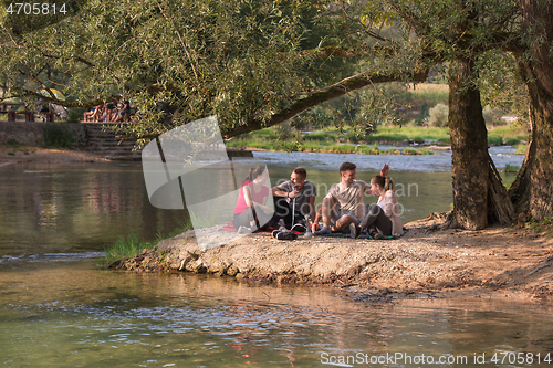 Image of friends smoking hookah on the river bank