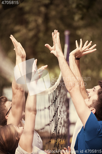 Image of group of young friends playing Beach volleyball