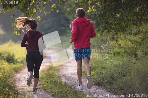 Image of young couple jogging along a country road