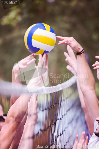 Image of group of young friends playing Beach volleyball