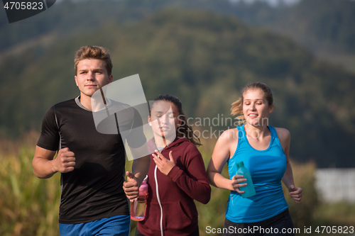 Image of young people jogging on country road