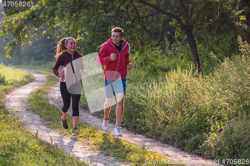 Image of young couple jogging along a country road