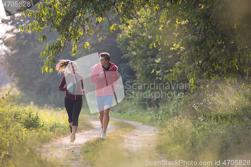 Image of young couple jogging along a country road
