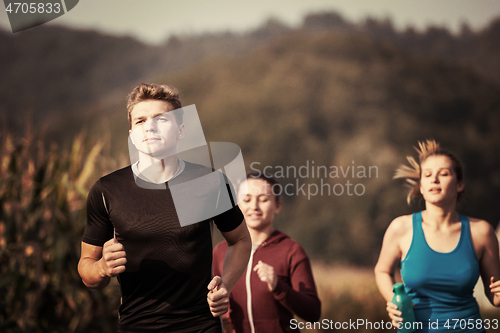 Image of young people jogging on country road