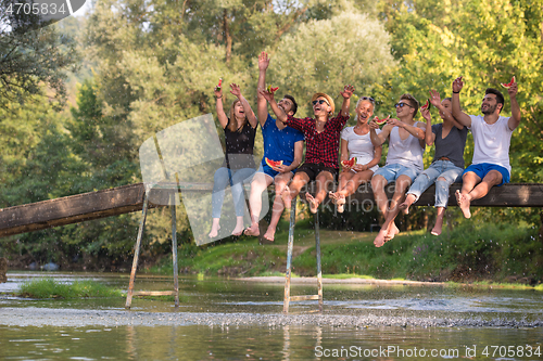 Image of friends enjoying watermelon while sitting on the wooden bridge