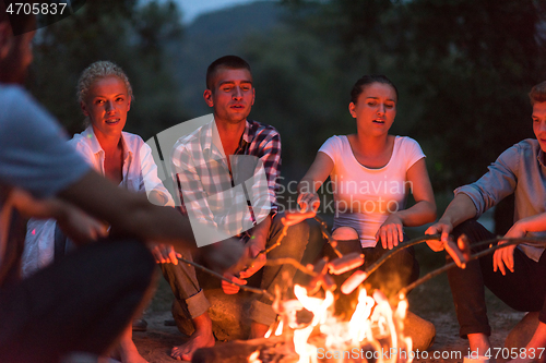 Image of young friends relaxing around campfire