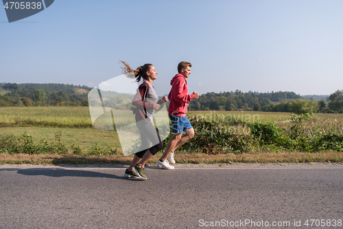 Image of young couple jogging along a country road