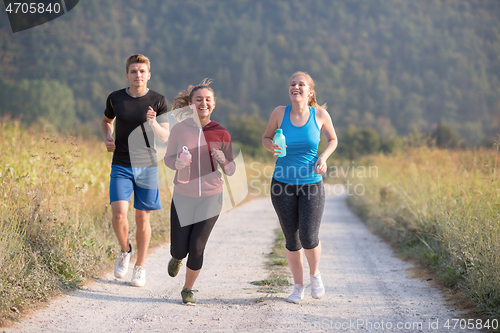 Image of young people jogging on country road