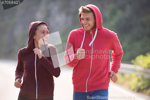 Image of young couple jogging along a country road