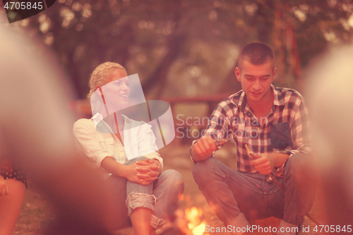 Image of young friends relaxing around campfire