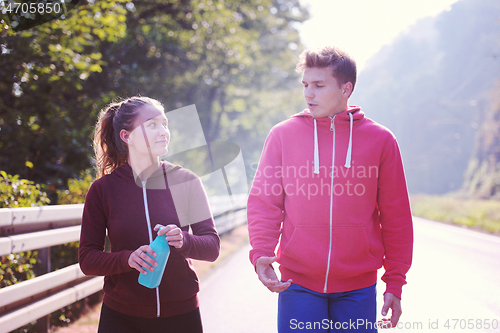 Image of young couple jogging along a country road