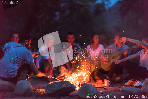 Image of young friends relaxing around campfire