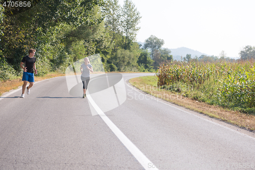 Image of young couple jogging along a country road