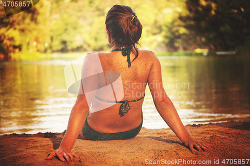 Image of girl in a green bikini relaxing on the riverbank