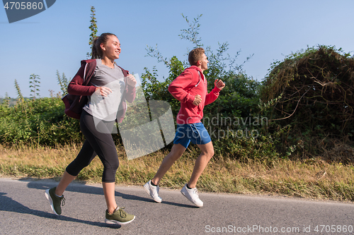 Image of young couple jogging along a country road