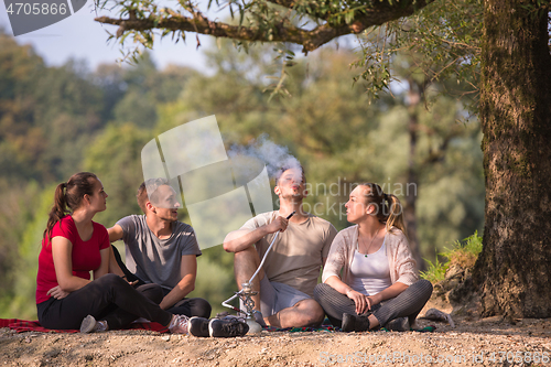 Image of friends smoking hookah on the river bank