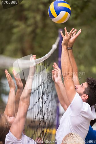 Image of group of young friends playing Beach volleyball