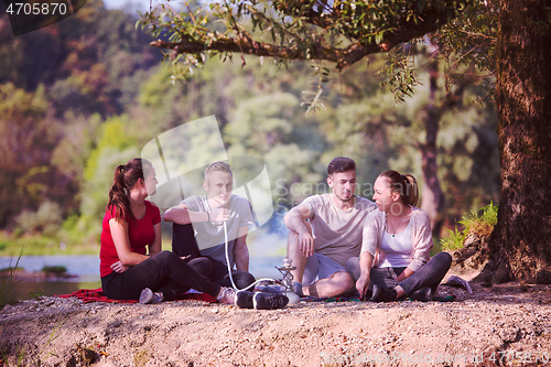 Image of friends smoking hookah on the river bank