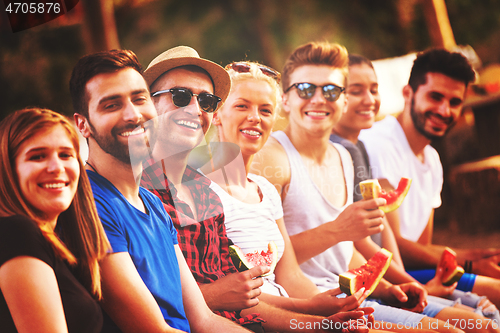 Image of friends enjoying watermelon while sitting on the wooden bridge