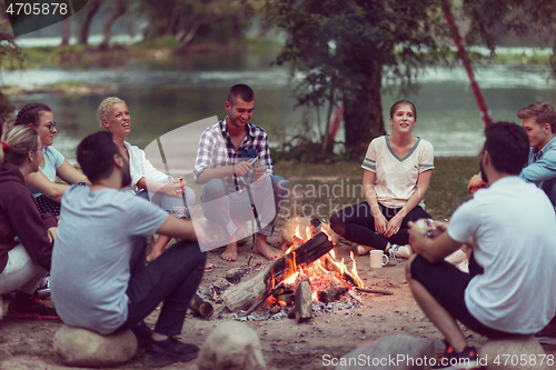 Image of young friends relaxing around campfire