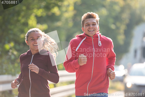 Image of young couple jogging along a country road