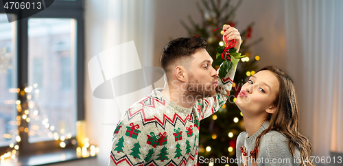 Image of happy couple kissing under mistletoe on christmas