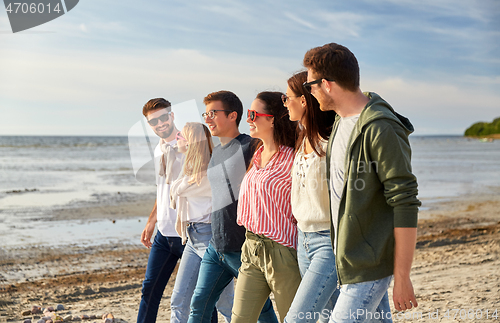 Image of happy friends walking along summer beach