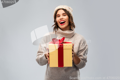 Image of young woman in knitted winter hat holding gift box