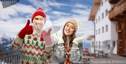 Image of couple in ugly christmas sweaters over ski resort