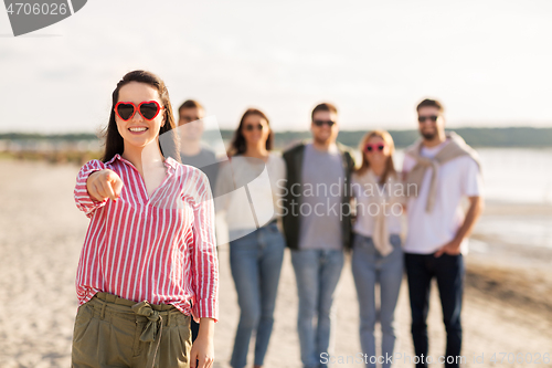 Image of woman with friends on beach pointing to you