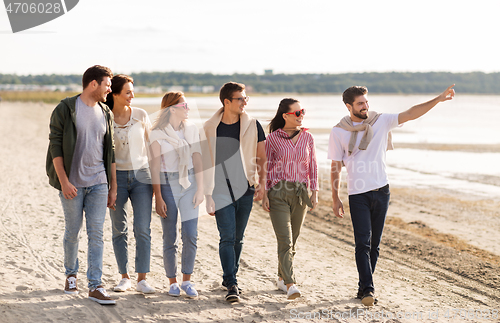 Image of happy friends walking along summer beach