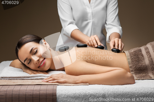 Image of beautiful woman having hot stone massage at spa