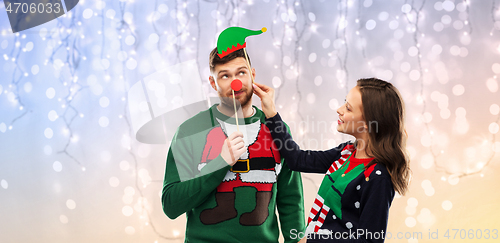 Image of couple with christmas party props in ugly sweaters