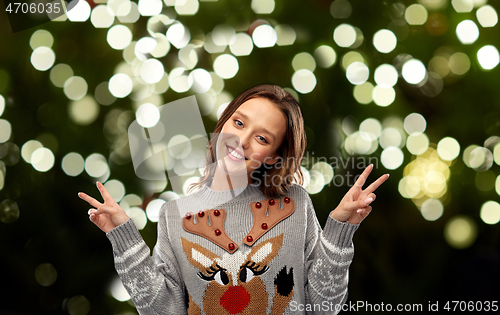 Image of woman in ugly christmas sweater showing peace sign