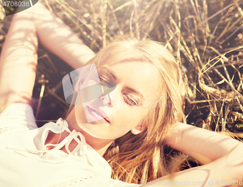 Image of happy young woman lying on cereal field or hay