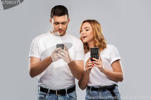 Image of happy couple in white t-shirts with smartphones