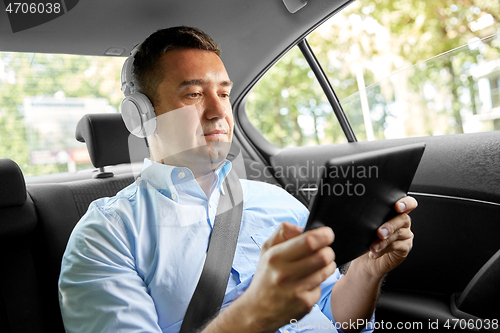 Image of passenger with headphones using tablet pc in car