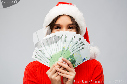 Image of happy woman in santa hat with money on christmas