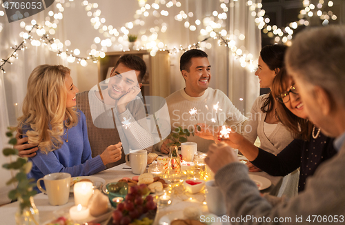 Image of family with sparklers having dinner party at home