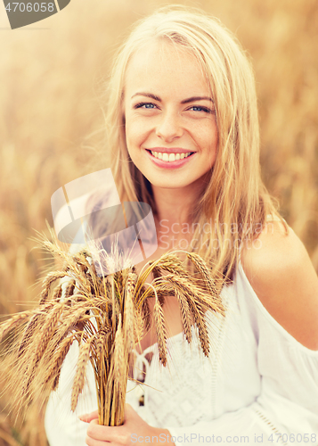 Image of happy young woman with spikelets on cereal field