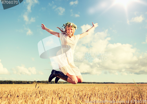 Image of happy woman in wreath jumping on cereal field