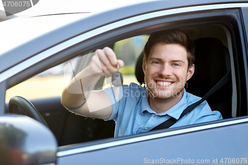 Image of smiling man or driver with key sitting in car