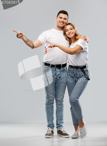 Image of happy couple in white t-shirts pointing fingers